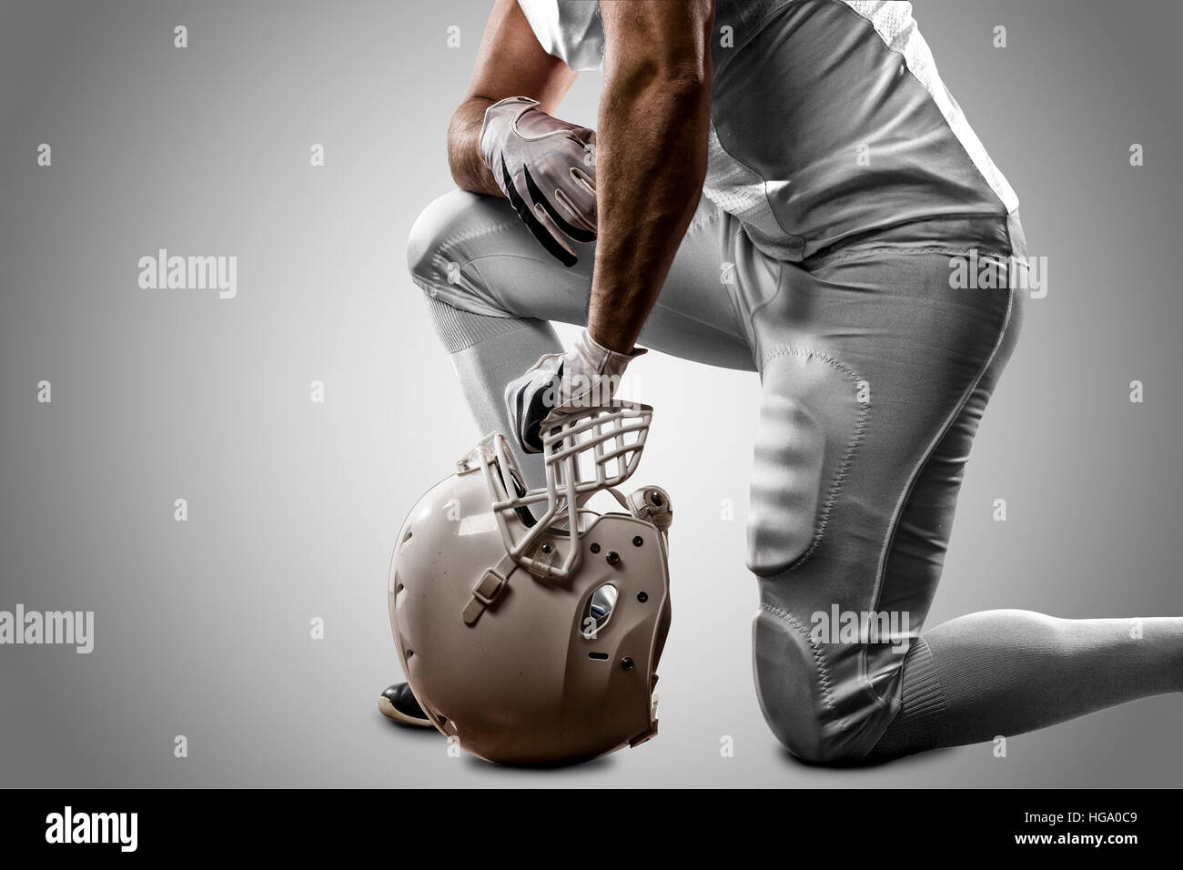 Football Player with a white uniform on his knees, on a white