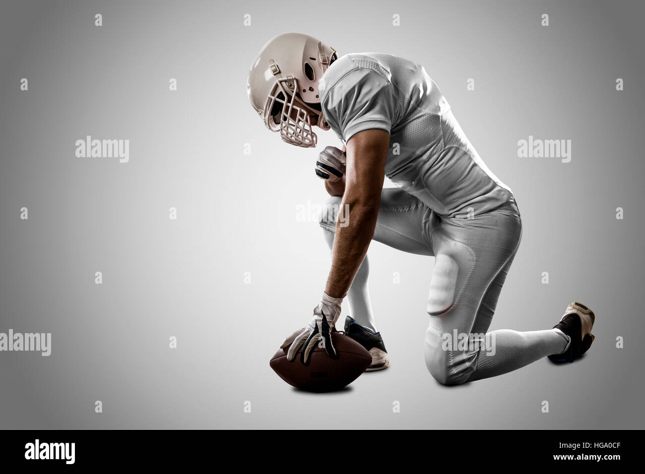 Football Player with a white uniform on his knees, on a white