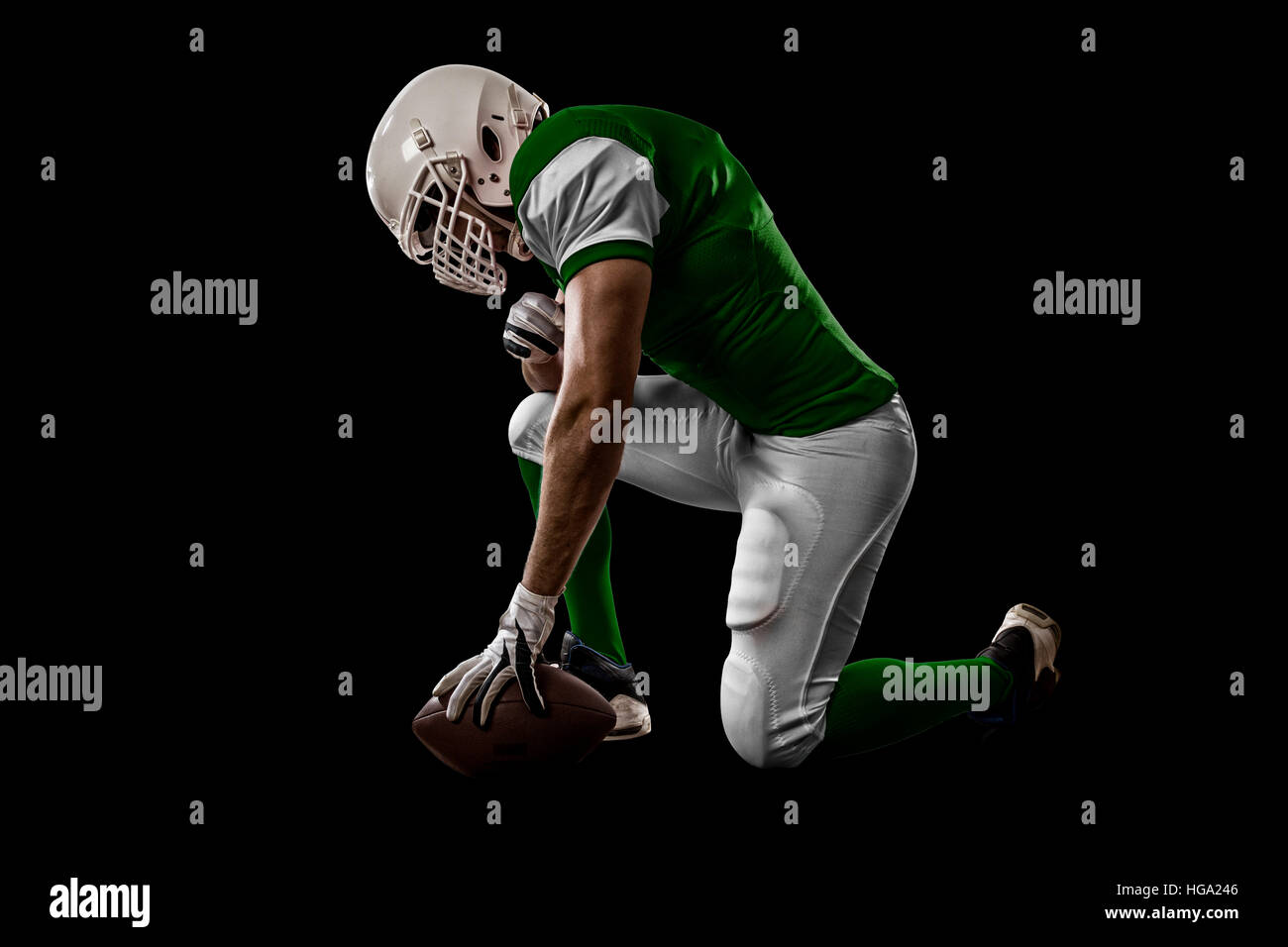 Football Player with a Green uniform on his knees, on a black