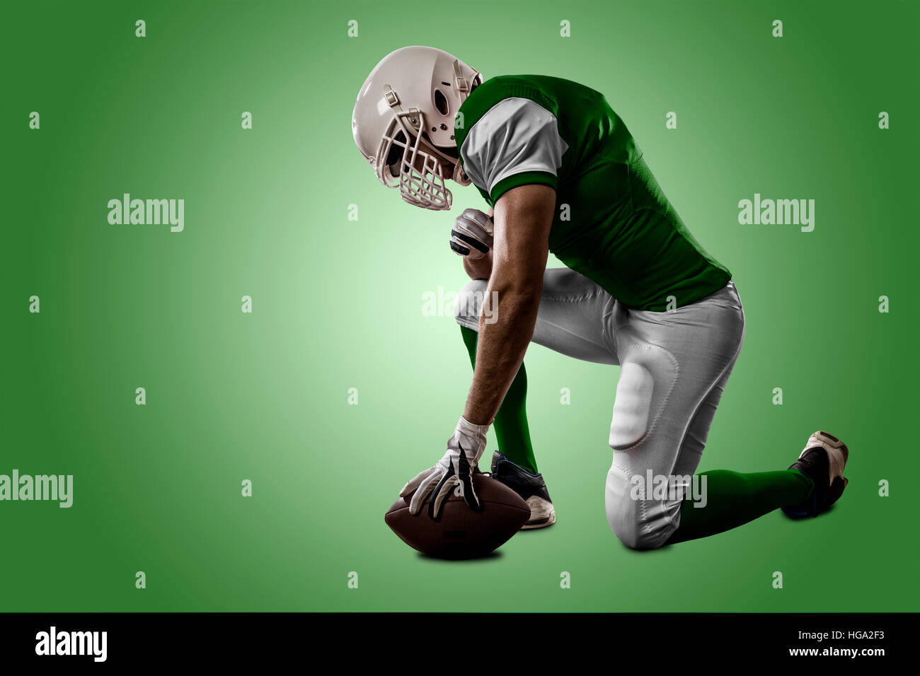 Football Player with a green uniform on his knees, on a green