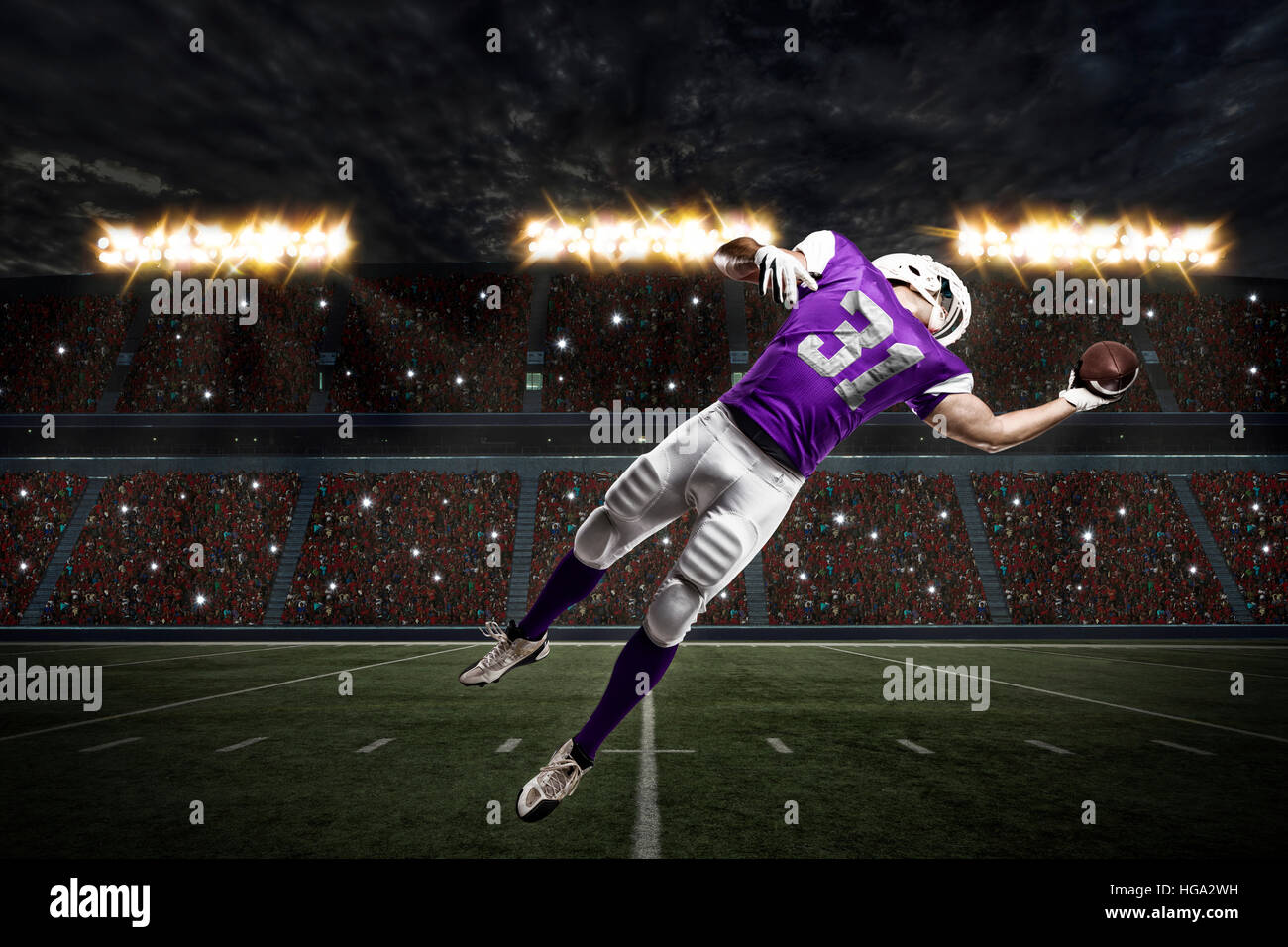 Football Player with a purple uniform catching a ball on a stadium. Stock Photo