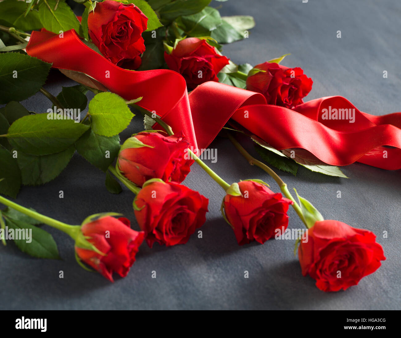 Grey Red Roses Grey stone with a bunch of red roses and a red ribbon Stock Photo - Alamy
