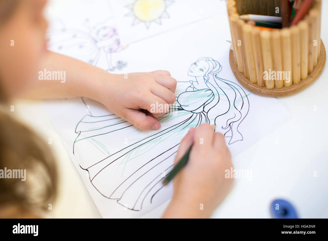 young girl coloring in coloring book. kids draws birthday party Stock Photo