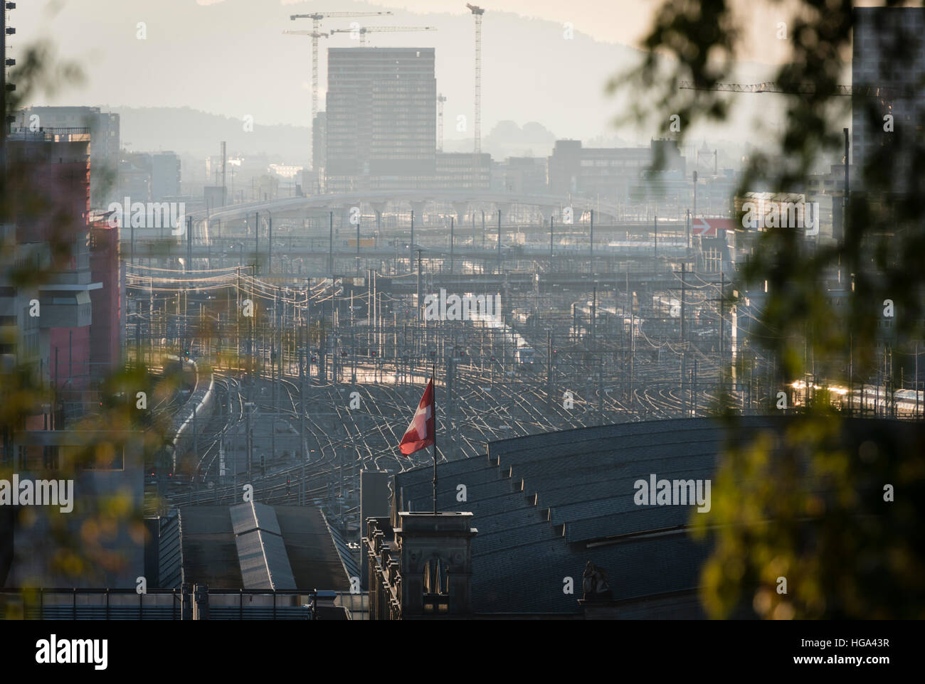 The Swiss flag is flying in the sunset on top of Zurich main station, one of Europe's busiest railway stations. Stock Photo