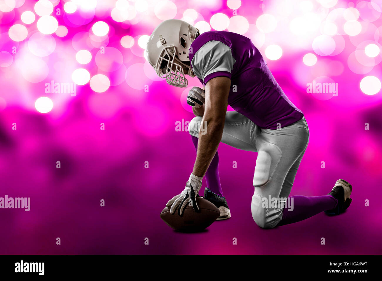 Football Player with a pink uniform on his knees, on a pink lights