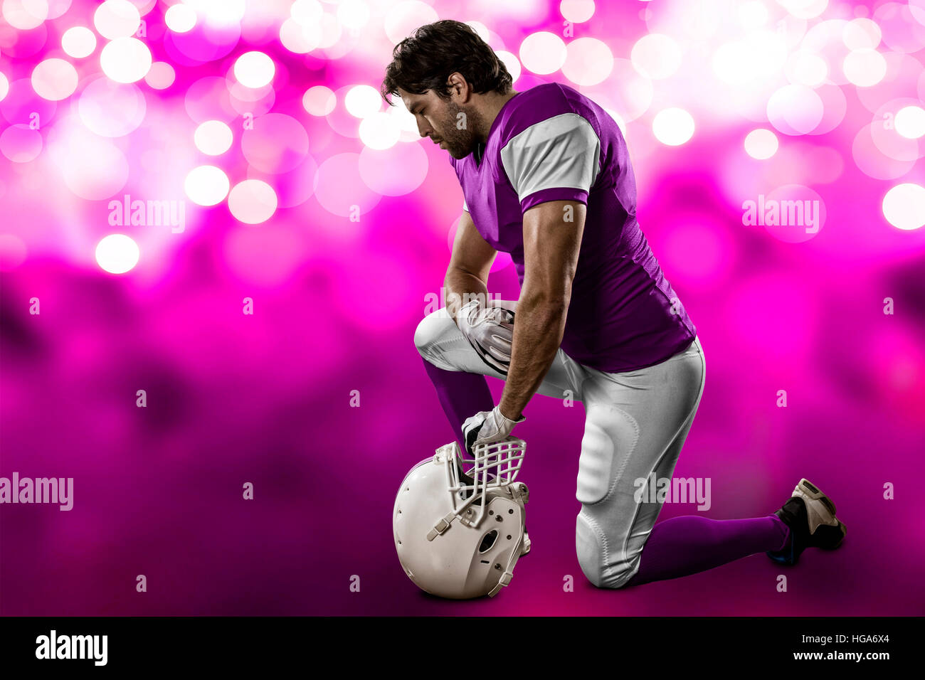 Football Player with a pink uniform on his knees, on a pink lights