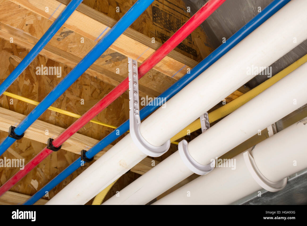 PEX and drain pipes attached to the basement ceiling of a home. Stock Photo
