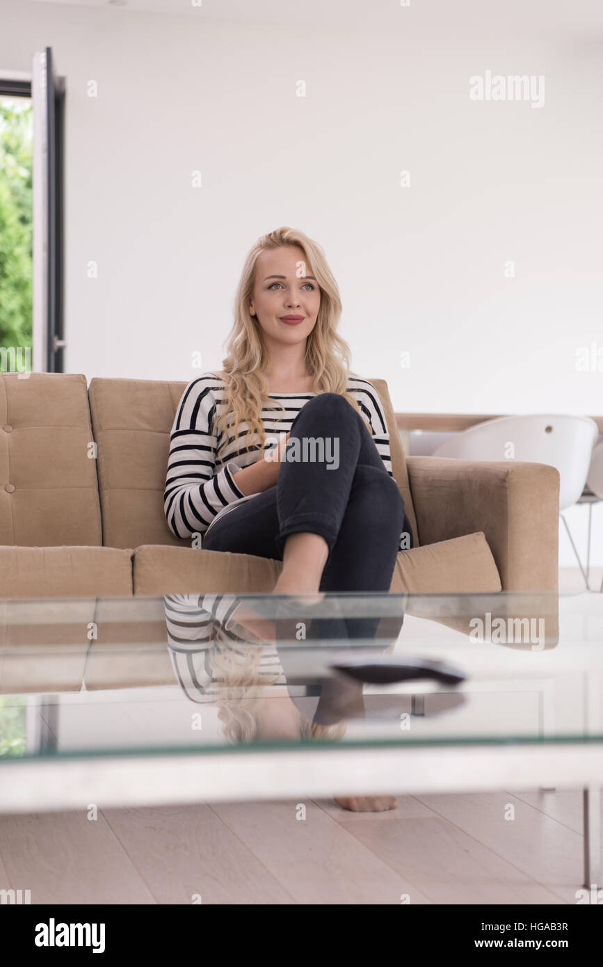 young happy woman sitting on sofa with mobile phone at luxury home ...