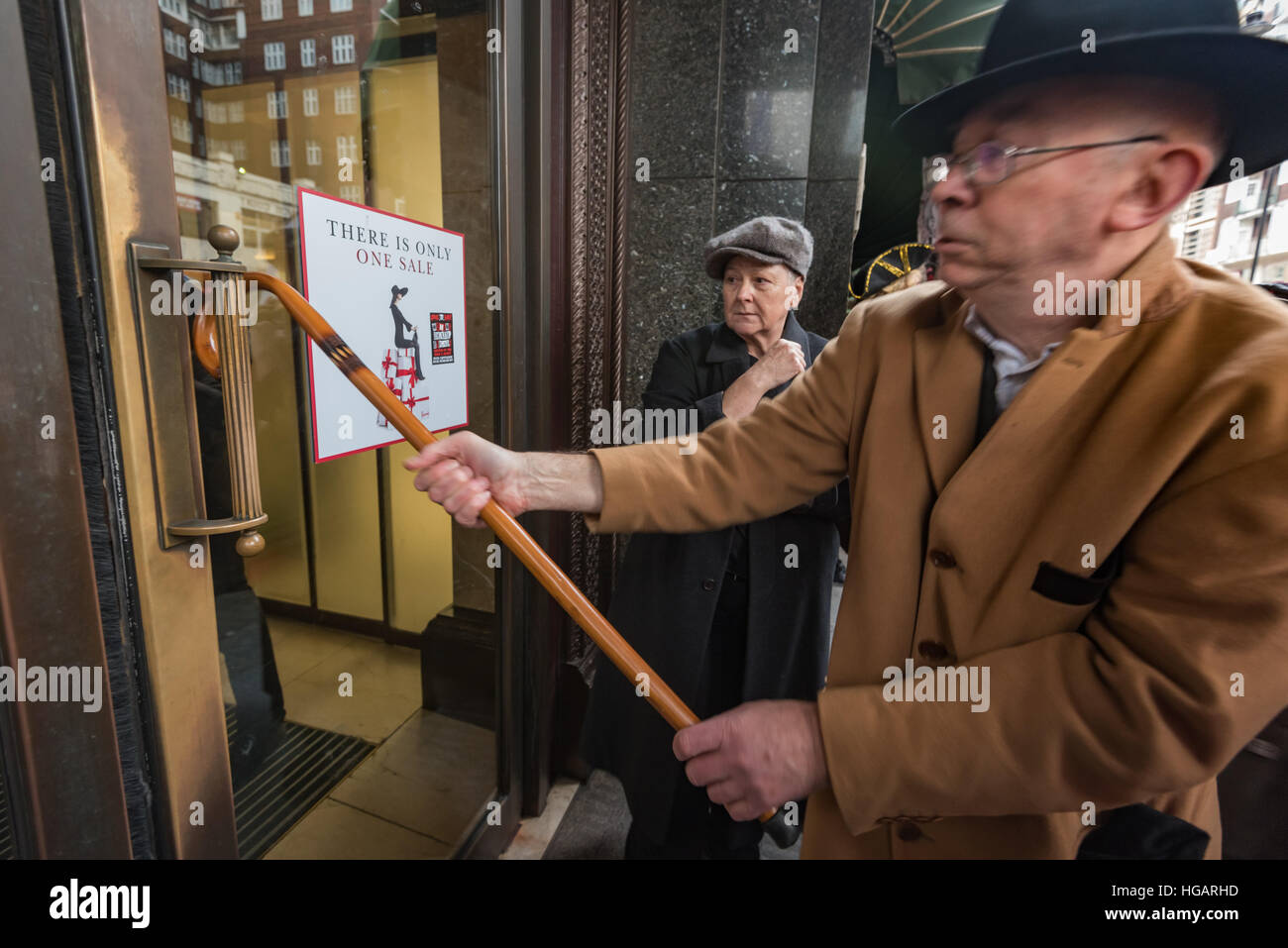 London, UK. 7th January 2017. Ian BOne of Class War hooks his walking stick around the door handle at Harrods as they support the protest by grass roots trade union United Voices of the World calling for 100% of the service charges to go to staff rather than the vast profits of the owners, the Qatari royal family. Credit: Peter Marshall/Alamy Live News Stock Photo