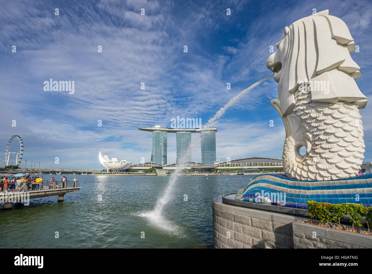 Singapore, Marina Bay, tourists admire the water spouting Merlion statue against the backdrop of the Marina Bay Sands resort und the Singapore Flyer Stock Photo