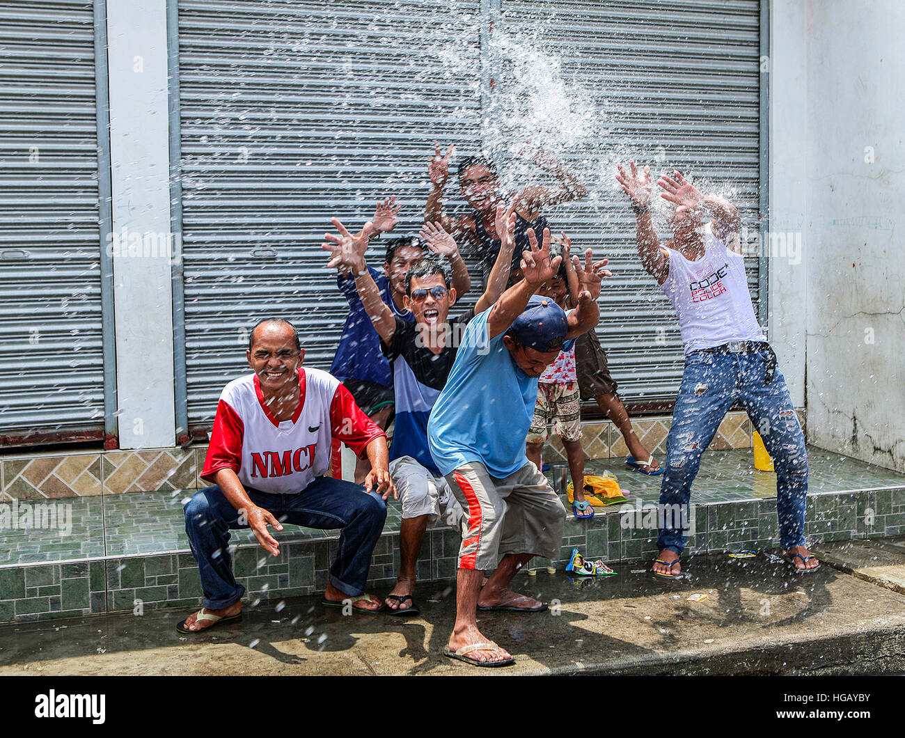 A group of happy Filipino men throw water on bystanders at the annual Roasted Pig Festival in Balayan, Philippines. Stock Photo