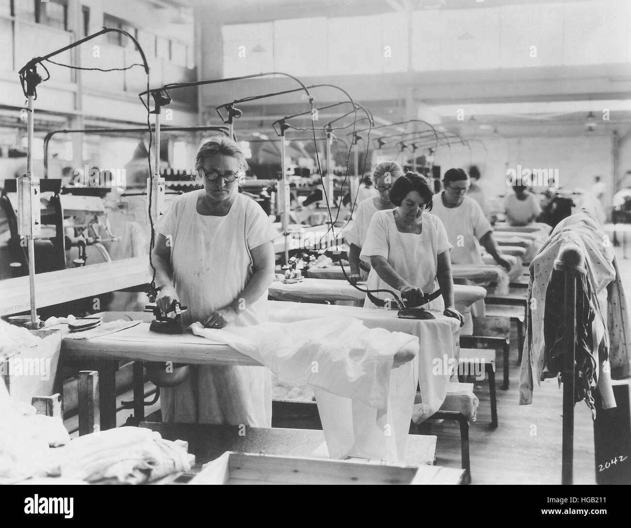 Older women doing hand ironing in laundry, circa 1920. Stock Photo