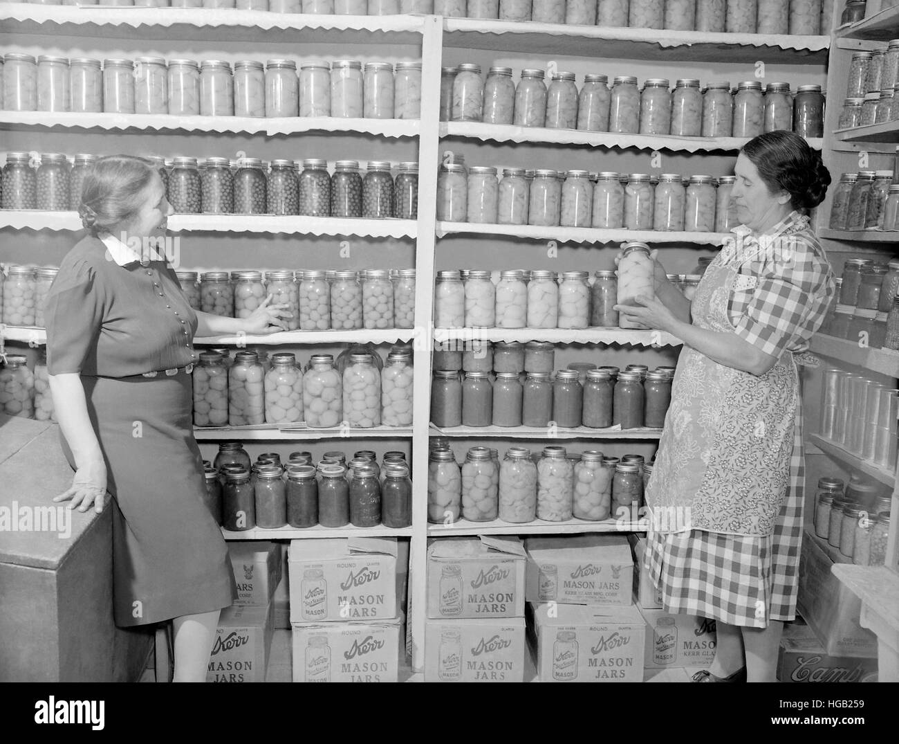 Two women standing in a kitchen pantry. circa 1946 Stock Photo