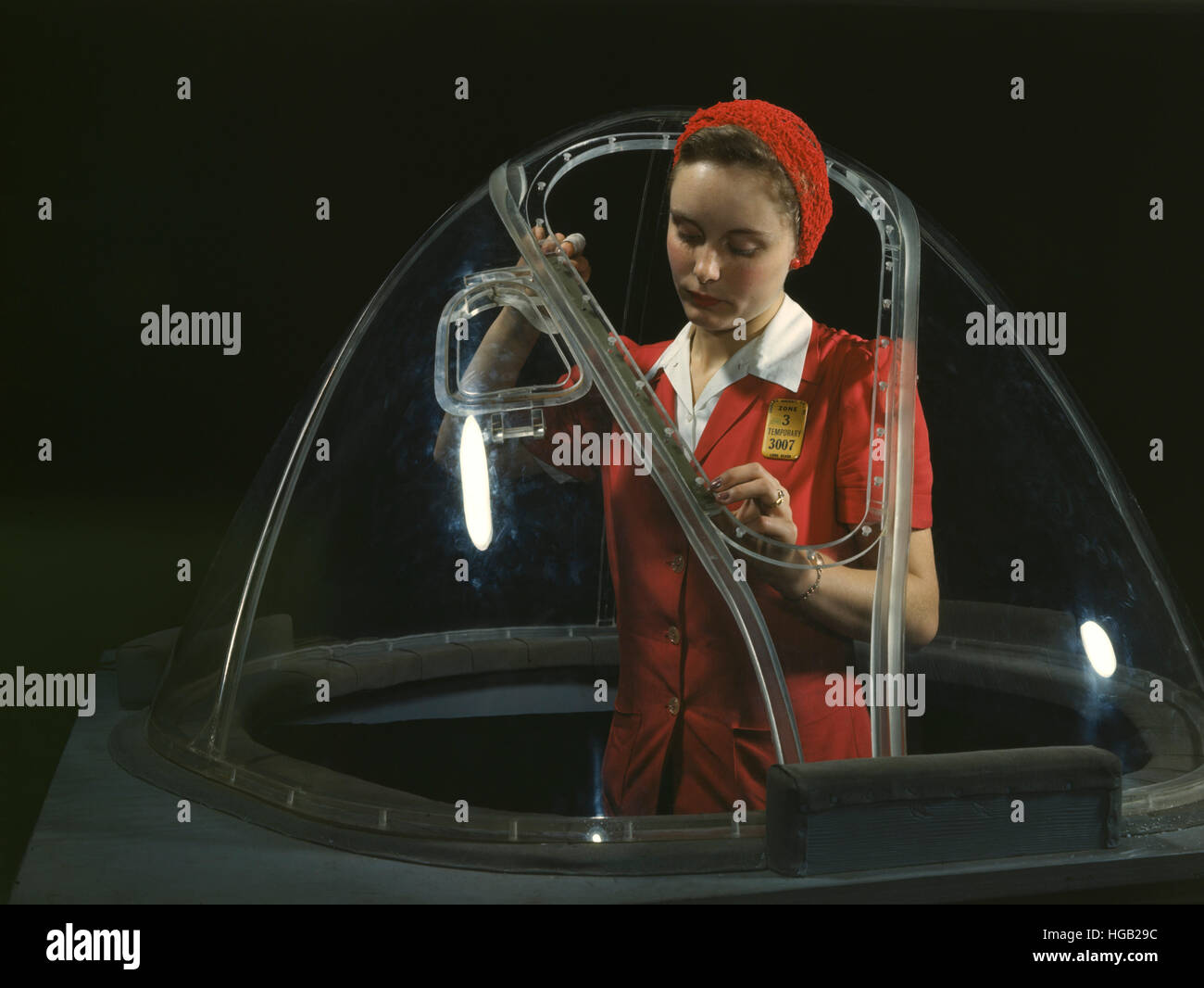 Woman putting finishing touches on the bombardier nose section of a B-17F bomber. Stock Photo