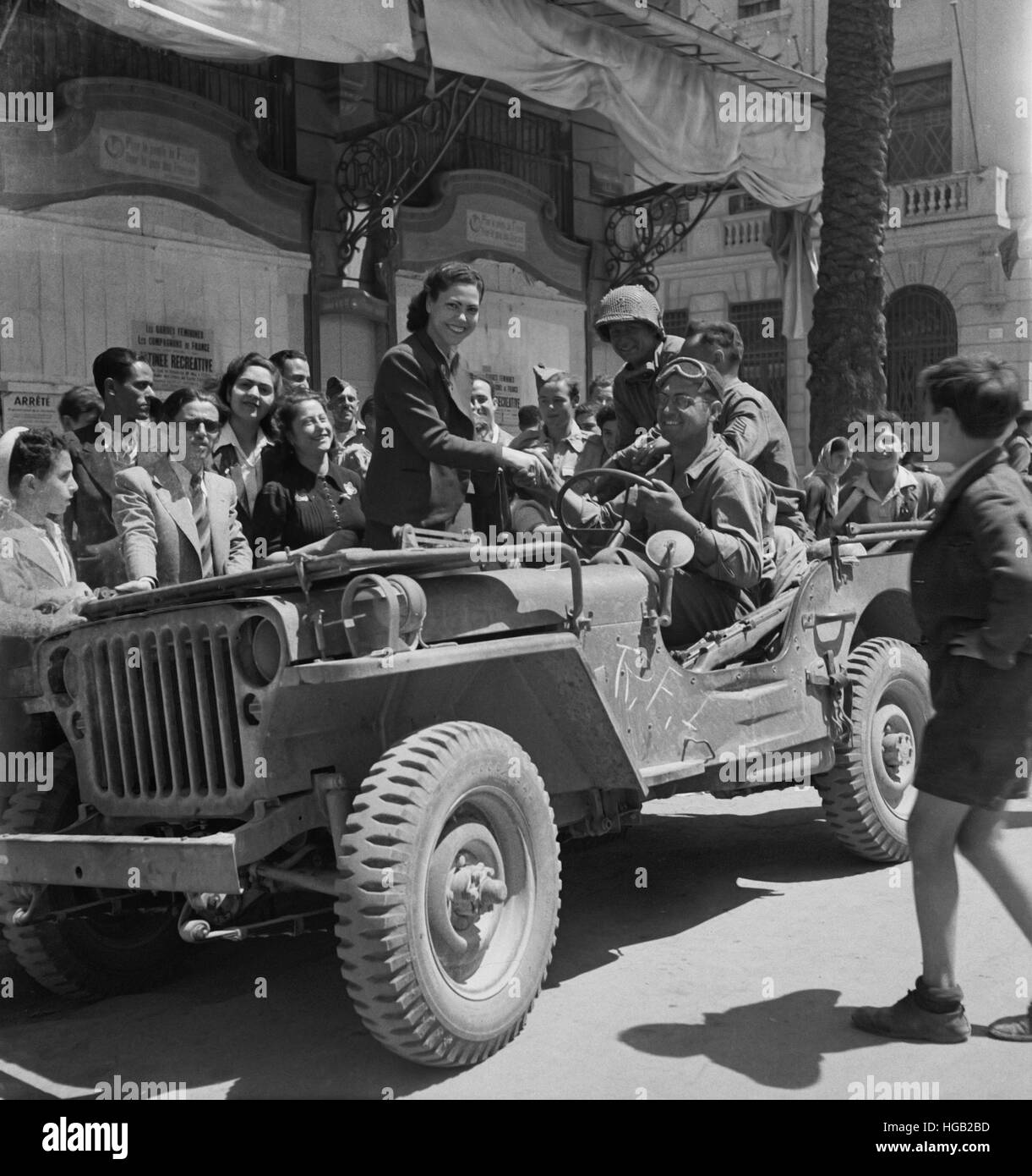 Girls climb on the Jeeps to greet American invading troops in the streets of Tunis, Tunisia, 1943. Stock Photo