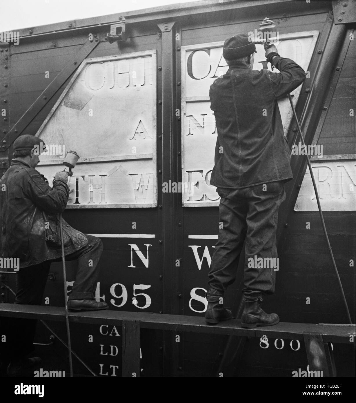 Workers stenciling the name of the railroad on newly painted freight cars. Stock Photo