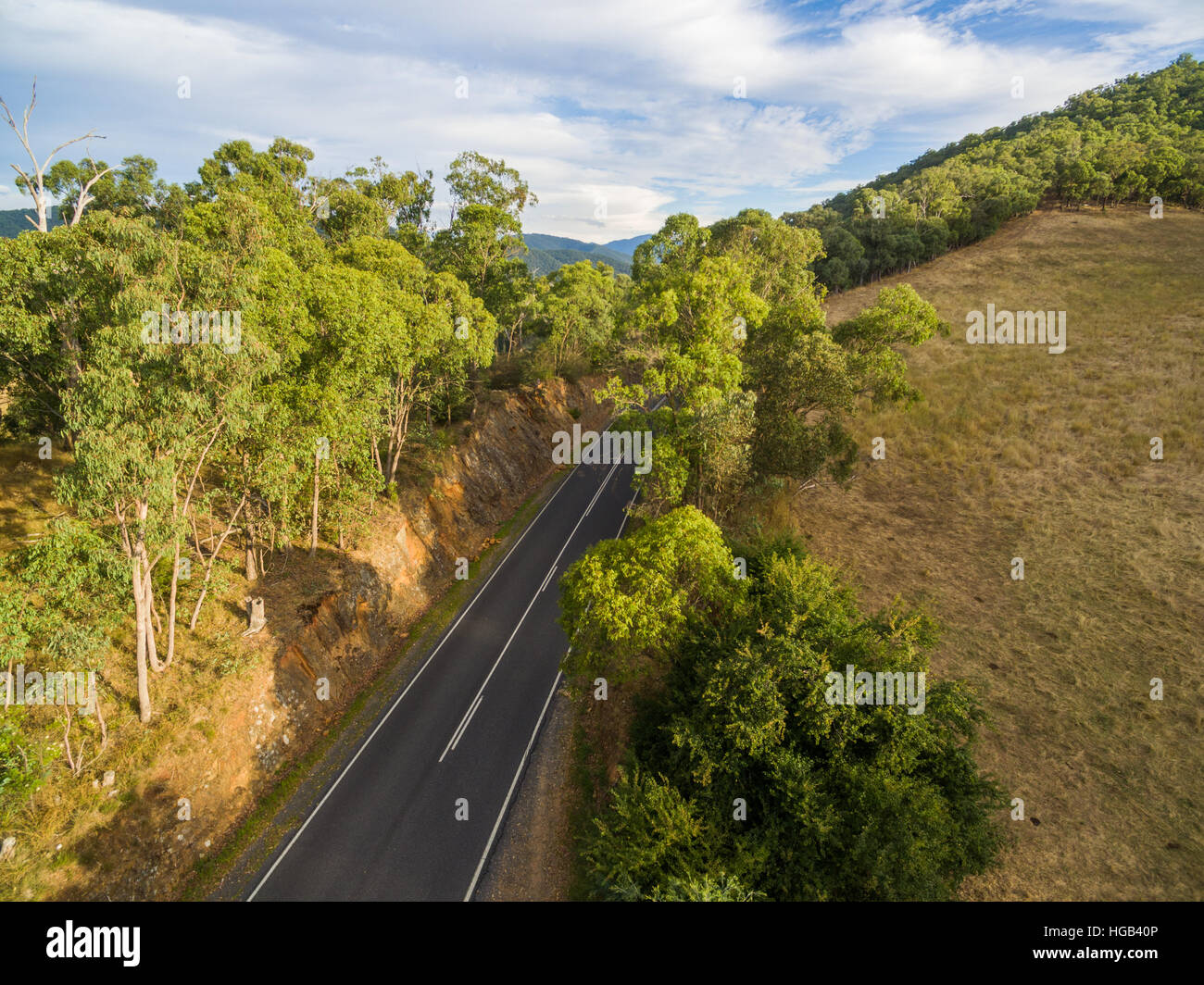Aerial view of rural road amongst hills and trees Stock Photo