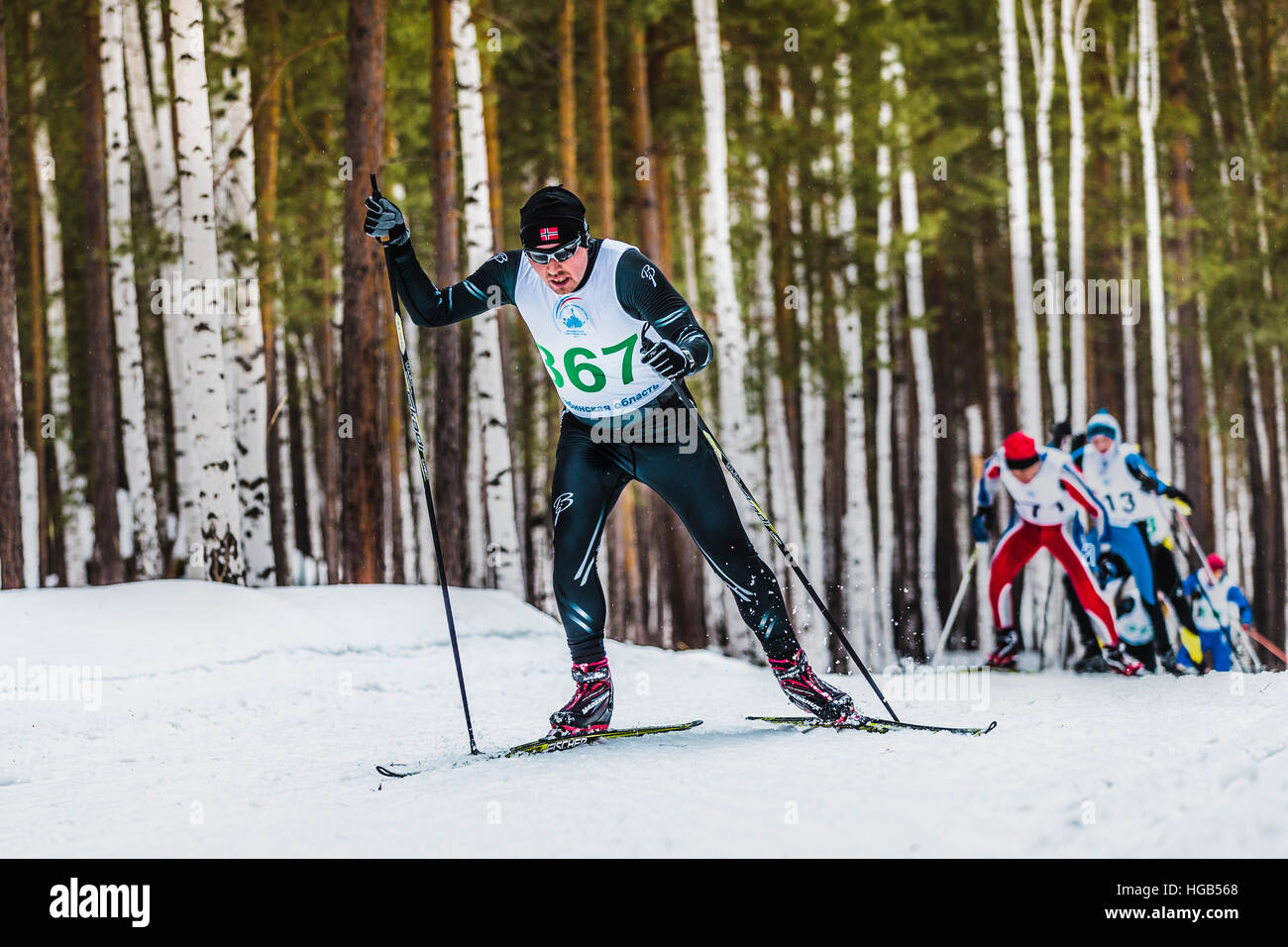 group of skiers men in winter forest free style in mountain during Championship on cross country skiing Stock Photo