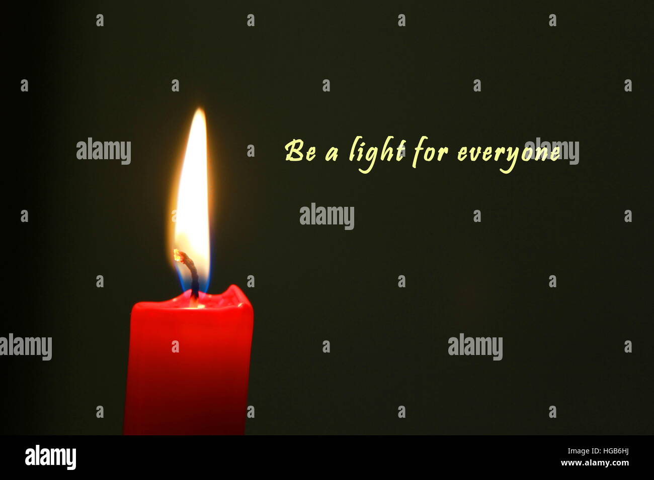 Red candle with flame illuminating dark background and english text Stock Photo