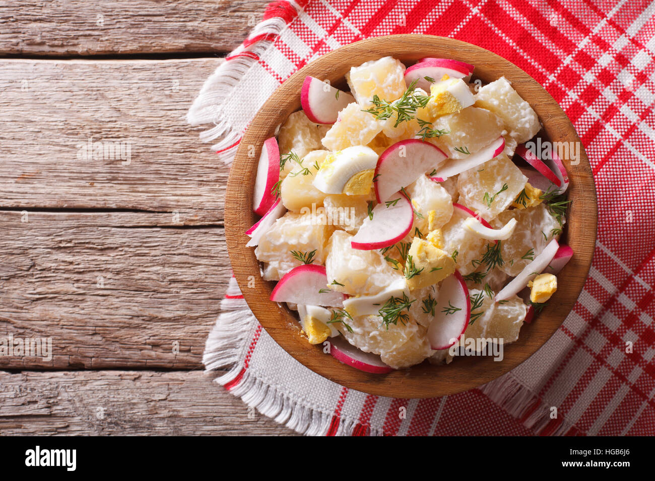 potato salad with radish and eggs in a bowl on the table. horizontal view from above Stock Photo