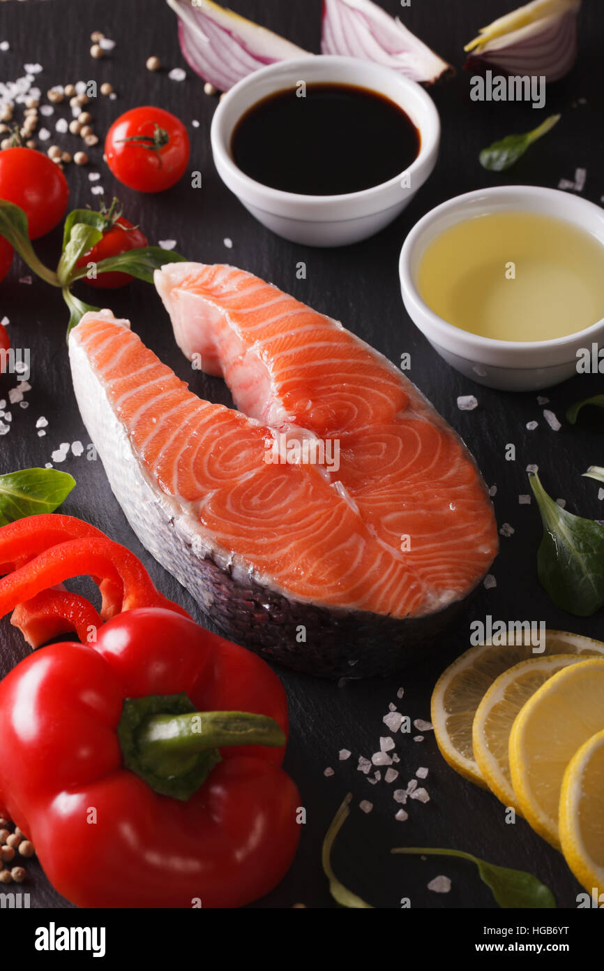 Raw salmon steak and ingredients on a slate board macro. Vertical Stock ...