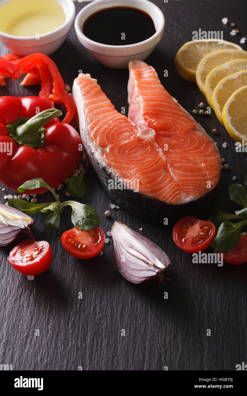 Raw salmon steak and ingredients on a slate board closeup. vertical ...