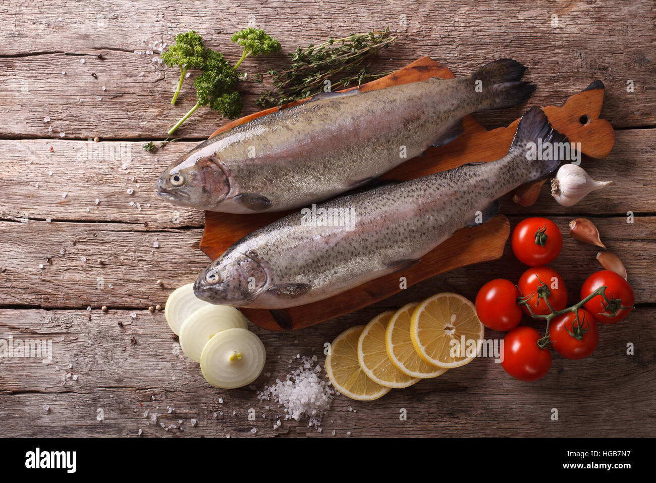 raw rainbow trout with ingredients on a wooden table. Horizontal top view Stock Photo