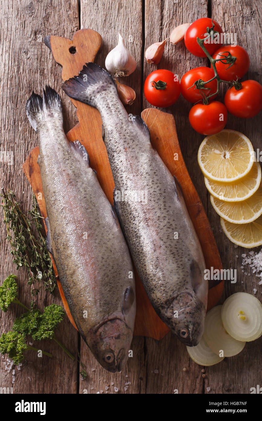raw rainbow trout with ingredients on a wooden table close-up. vertical top view Stock Photo