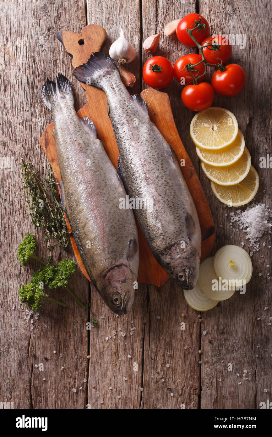 raw rainbow trout with ingredients on a wooden table. vertical top view Stock Photo