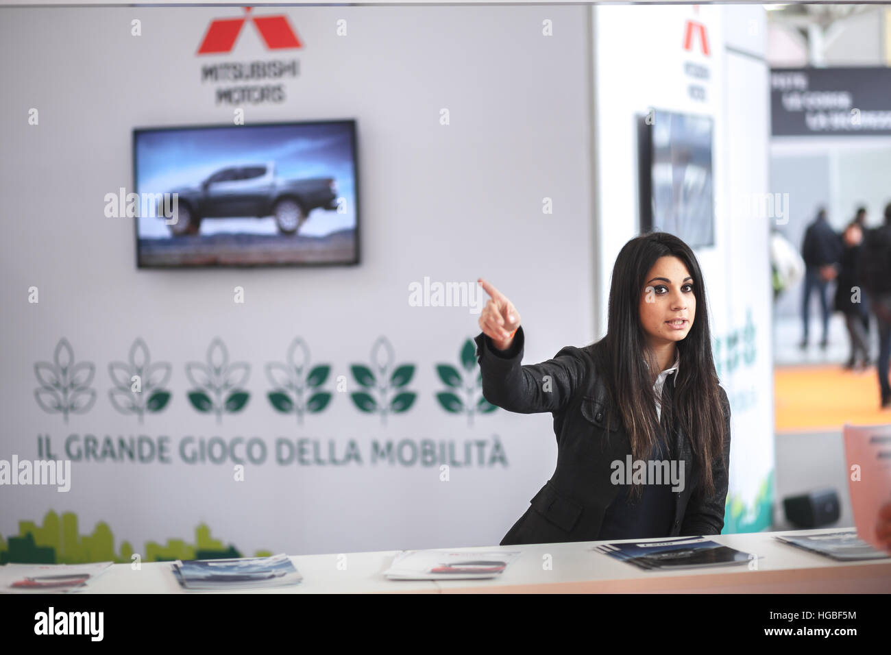 Italy, Bologna motor show 2016, Young receptionist from Mitsubishi exhibition booth giving indication Stock Photo