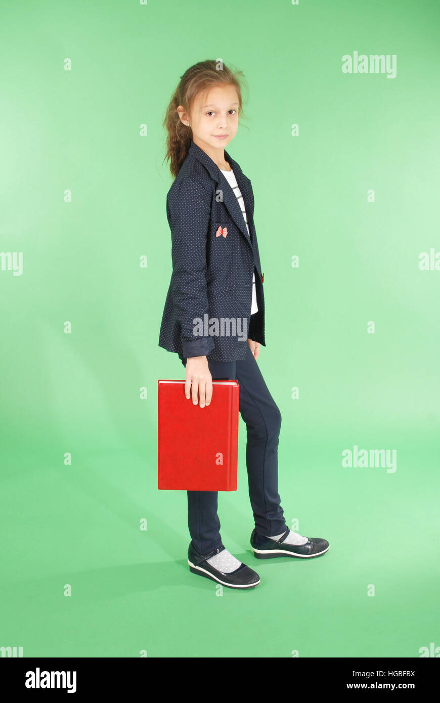 Young school girl with red book isolated on green Stock Photo - Alamy