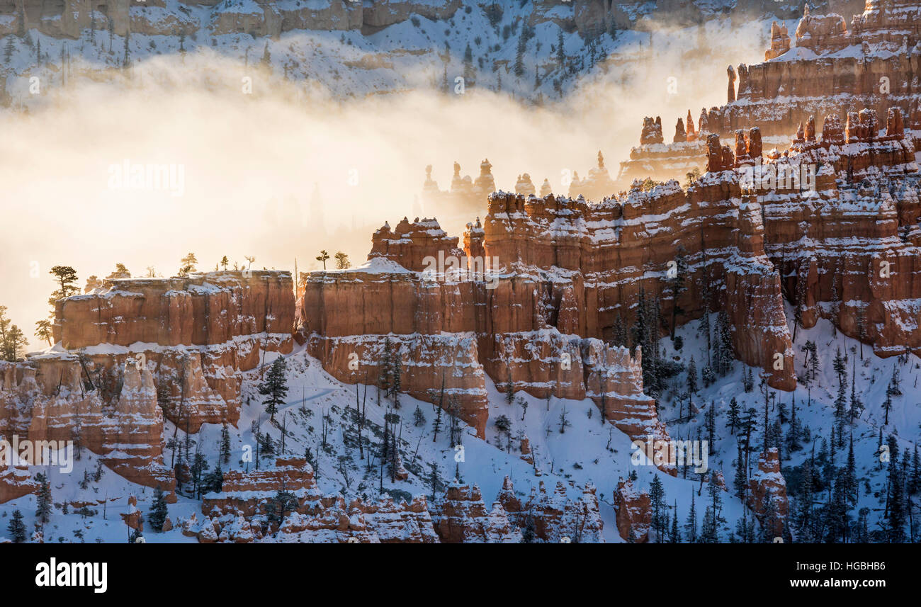 A ridge of hoodoos covered in snow and silhouetted against the fog in Bryce Canyon National Park, Utah Stock Photo