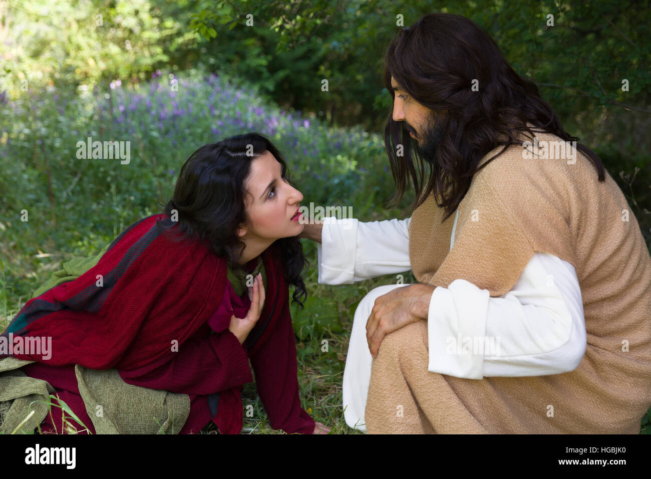 Repentant sinner woman touching the robe of Jesus, asking for forgiveness and healing Stock Photo