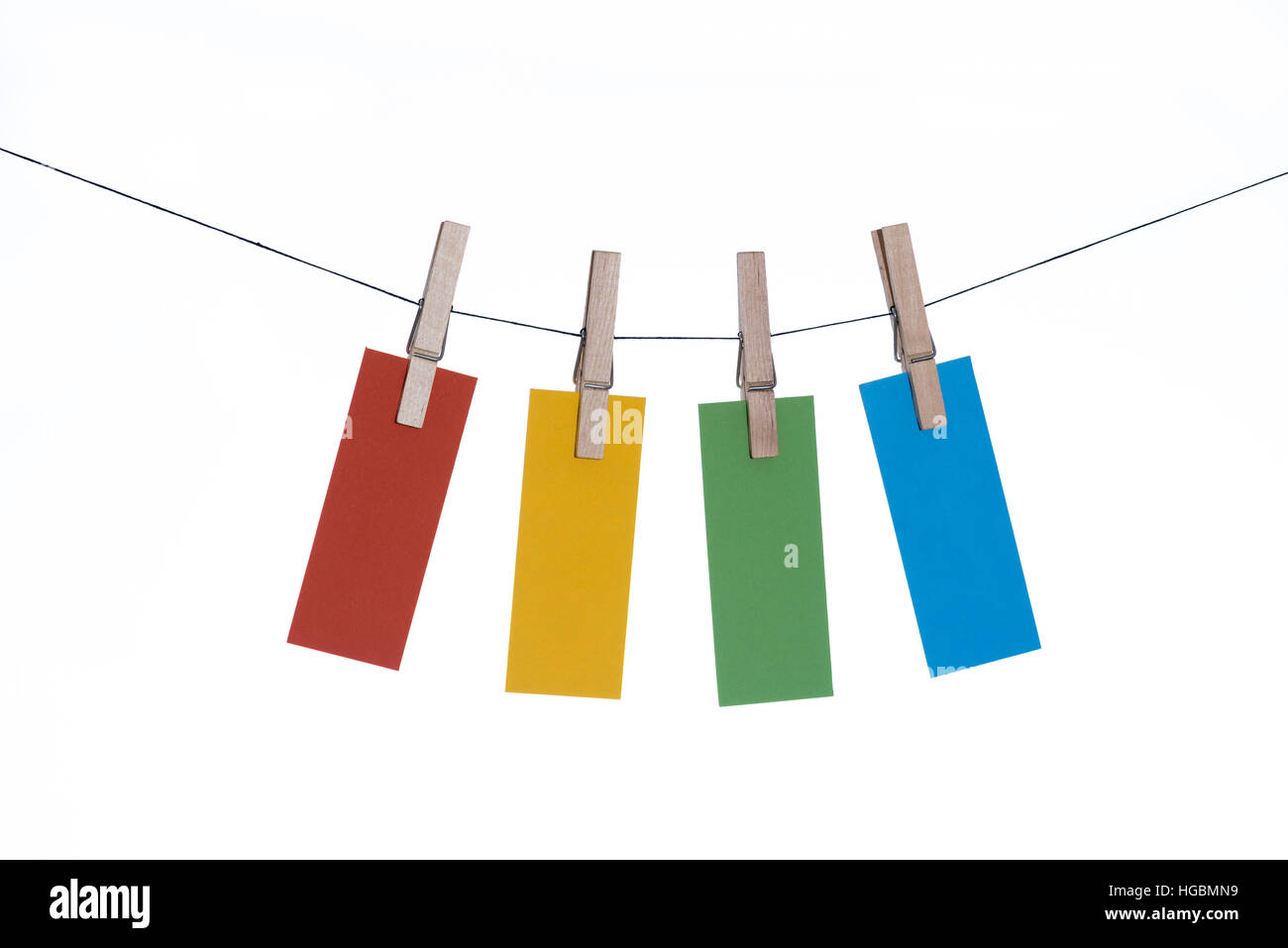 Hanging cards - four pieces of colored paper hanging from a line by clothes pegs Stock Photo