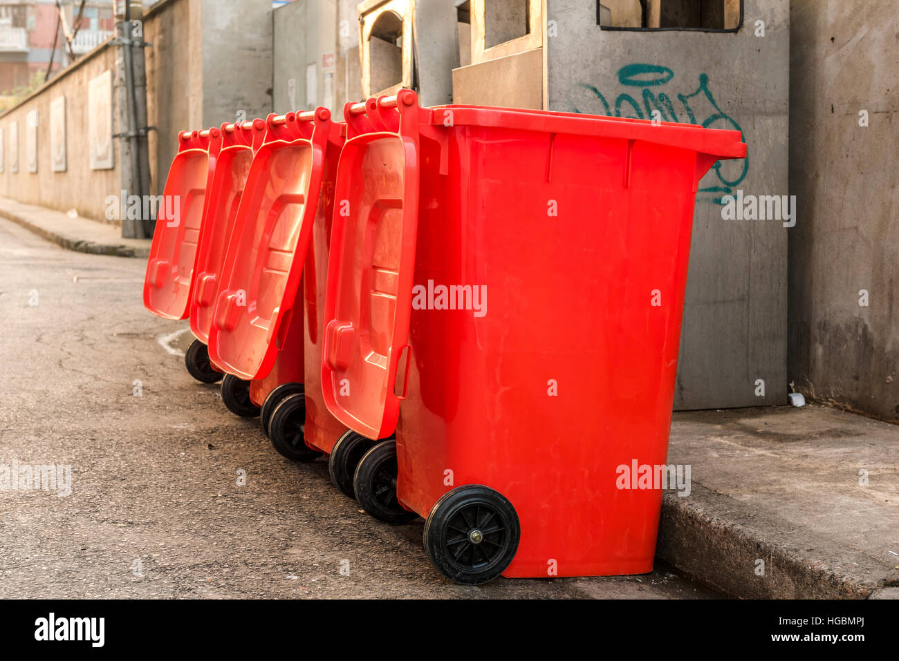 Red bins. Row of four plastic red trash bins on a street in China Stock