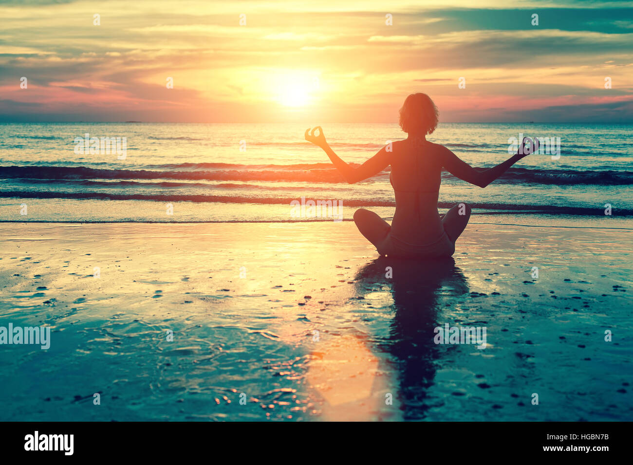 Silhouette young woman practicing yoga on the beach at ocean sunset ...
