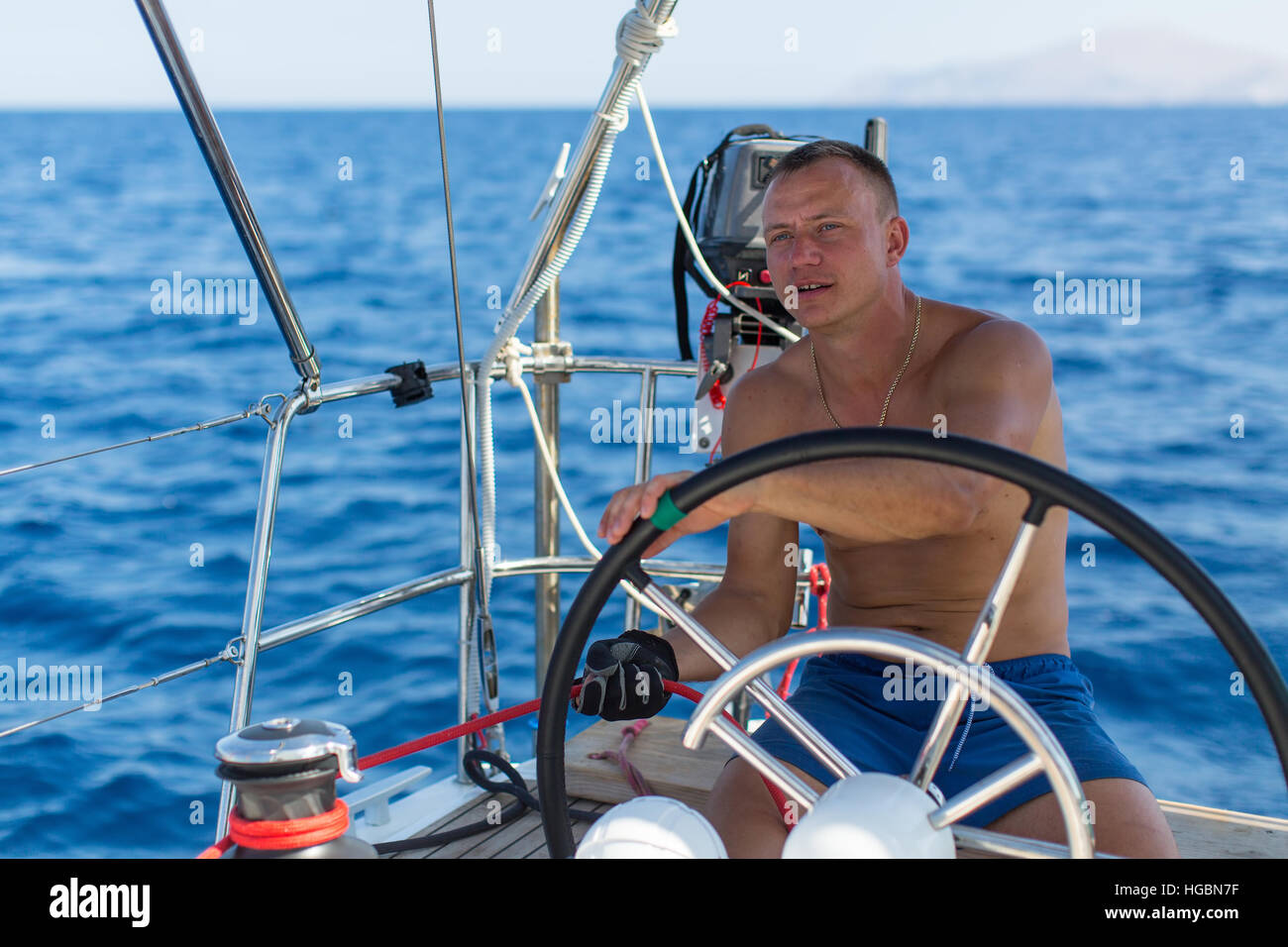 Man captain at the helm controls of a sailing boat during sea yacht