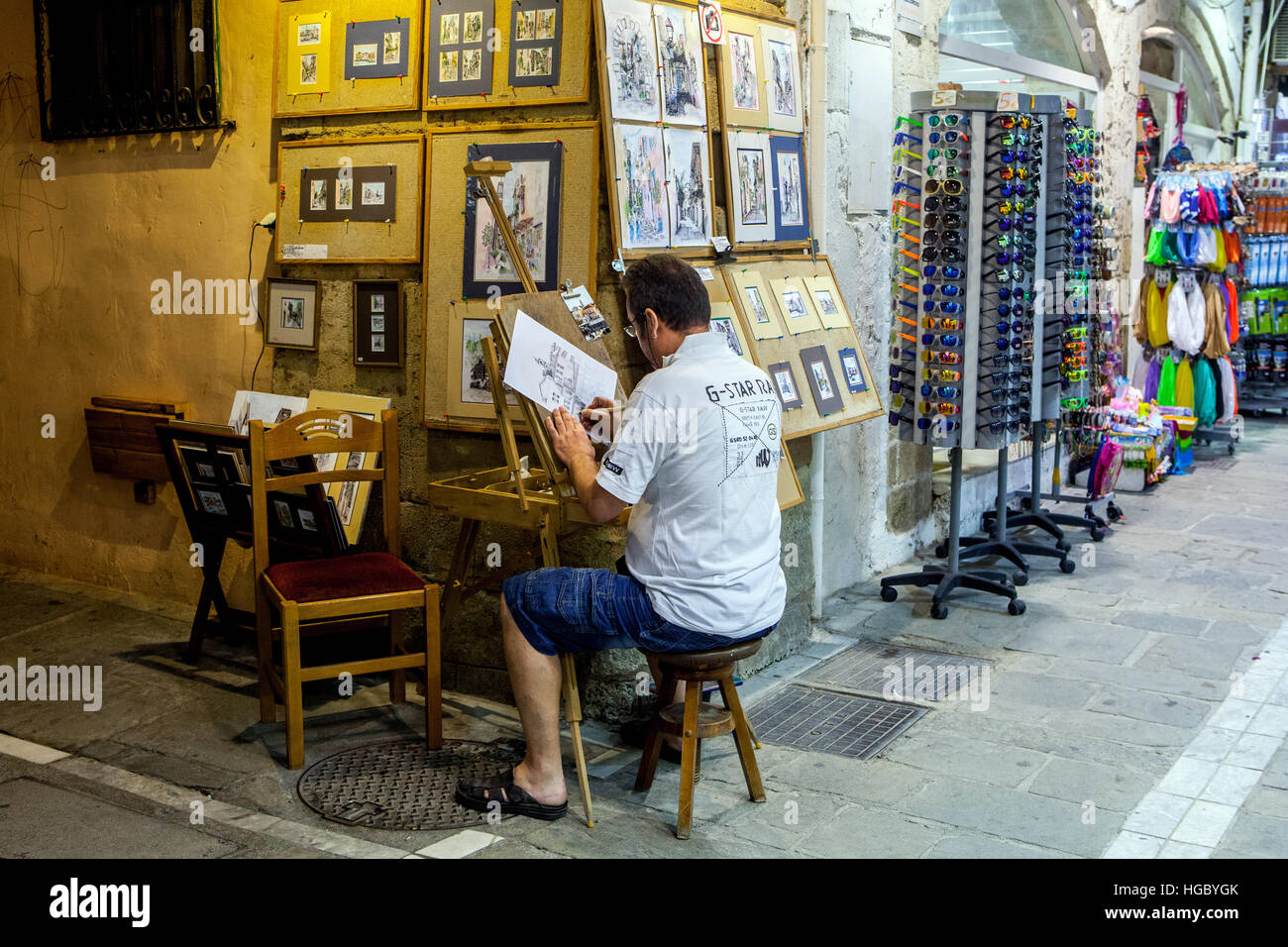 The man on the street in front of his store with art and souvenirs Rethymno, Crete, Greece Stock Photo