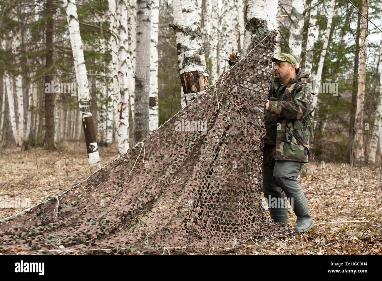 hunter placing camouflage netting Stock Photo Alamy