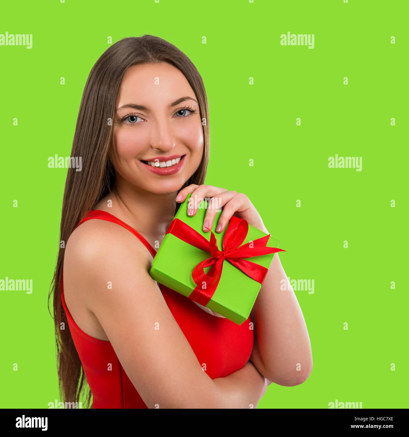 Portrait of a beautiful young happy woman with a gift on a green ...