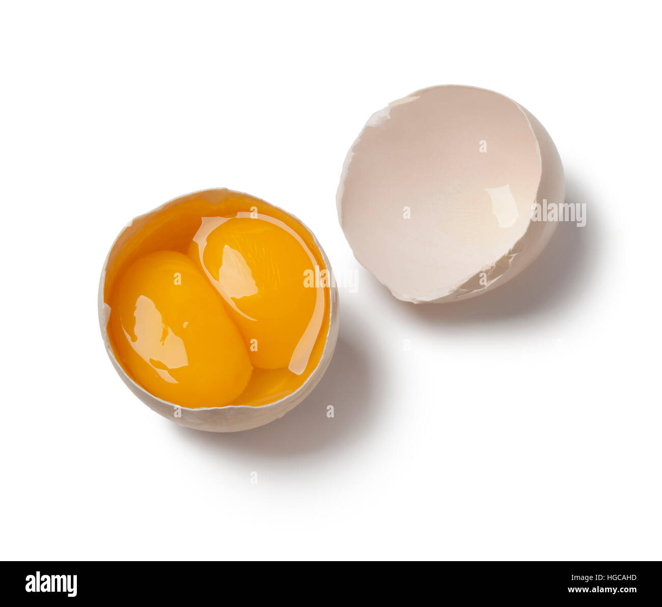 Broken raw double yolk egg in the shell isolated on white background Stock Photo