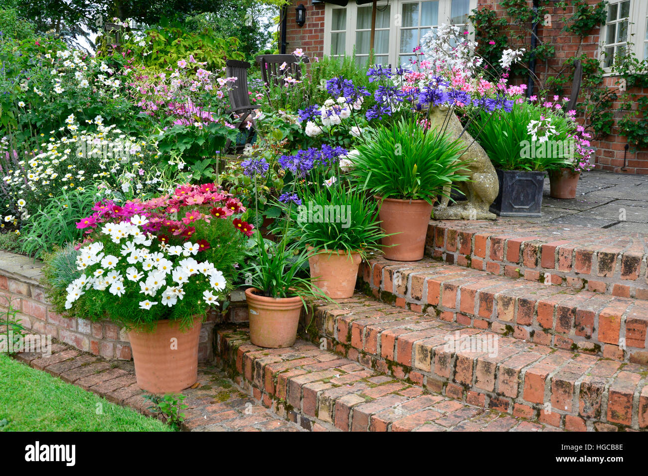 Colourful garden terrace with mixed flower beds and planted containers making a very attractice