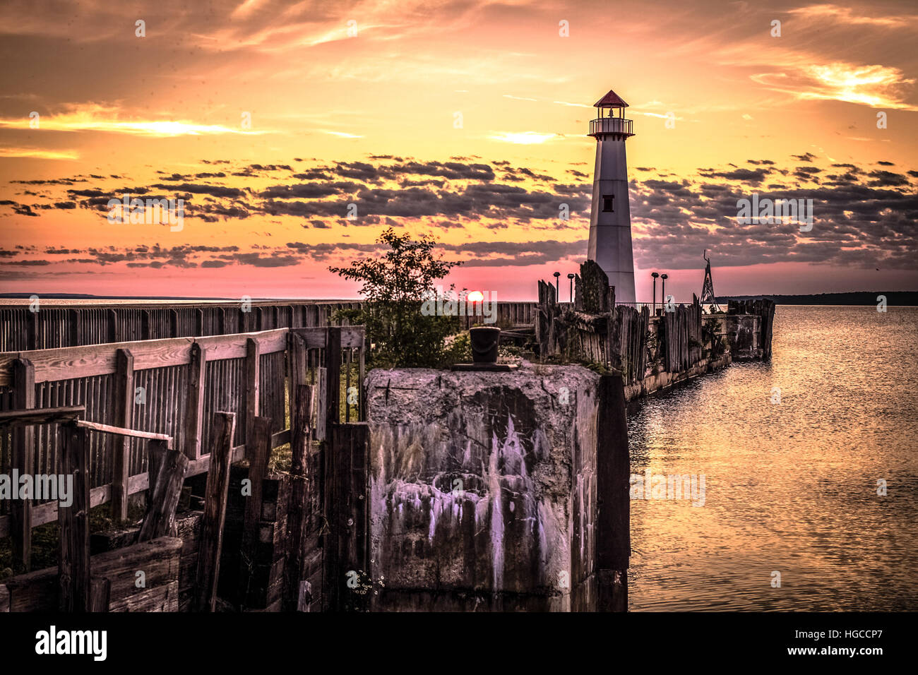 Coastal Lighthouse Sunrise. Sunrise horizon with a lighthouse and historic dock in the foreground in St. Ignace, Michigan. Stock Photo