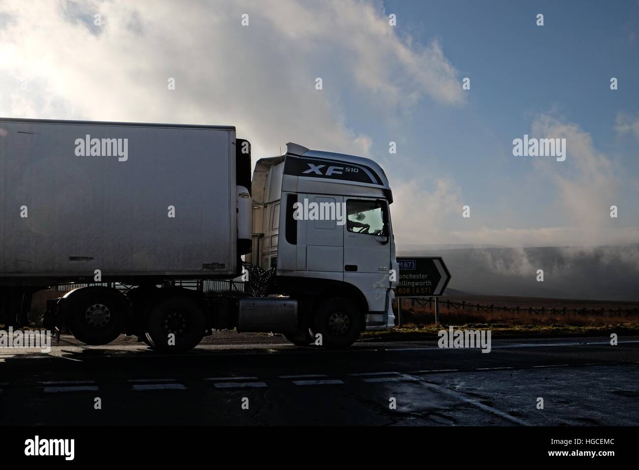 DAF XF truck running empty begins its westward descent of the A628 Woodhead pass in low cloud in Winter Stock Photo