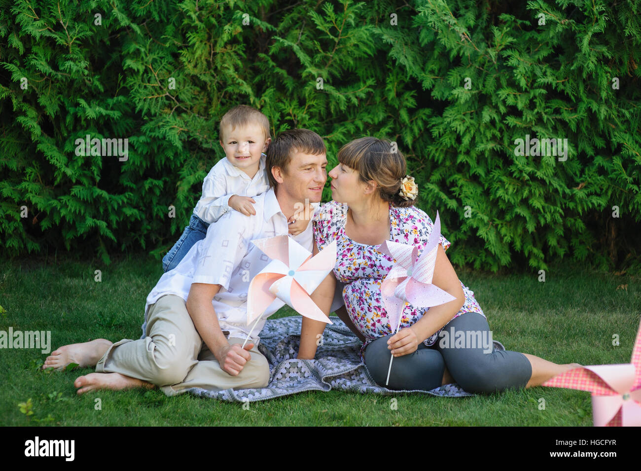 young family sitting on lawn in summer Park Stock Photo