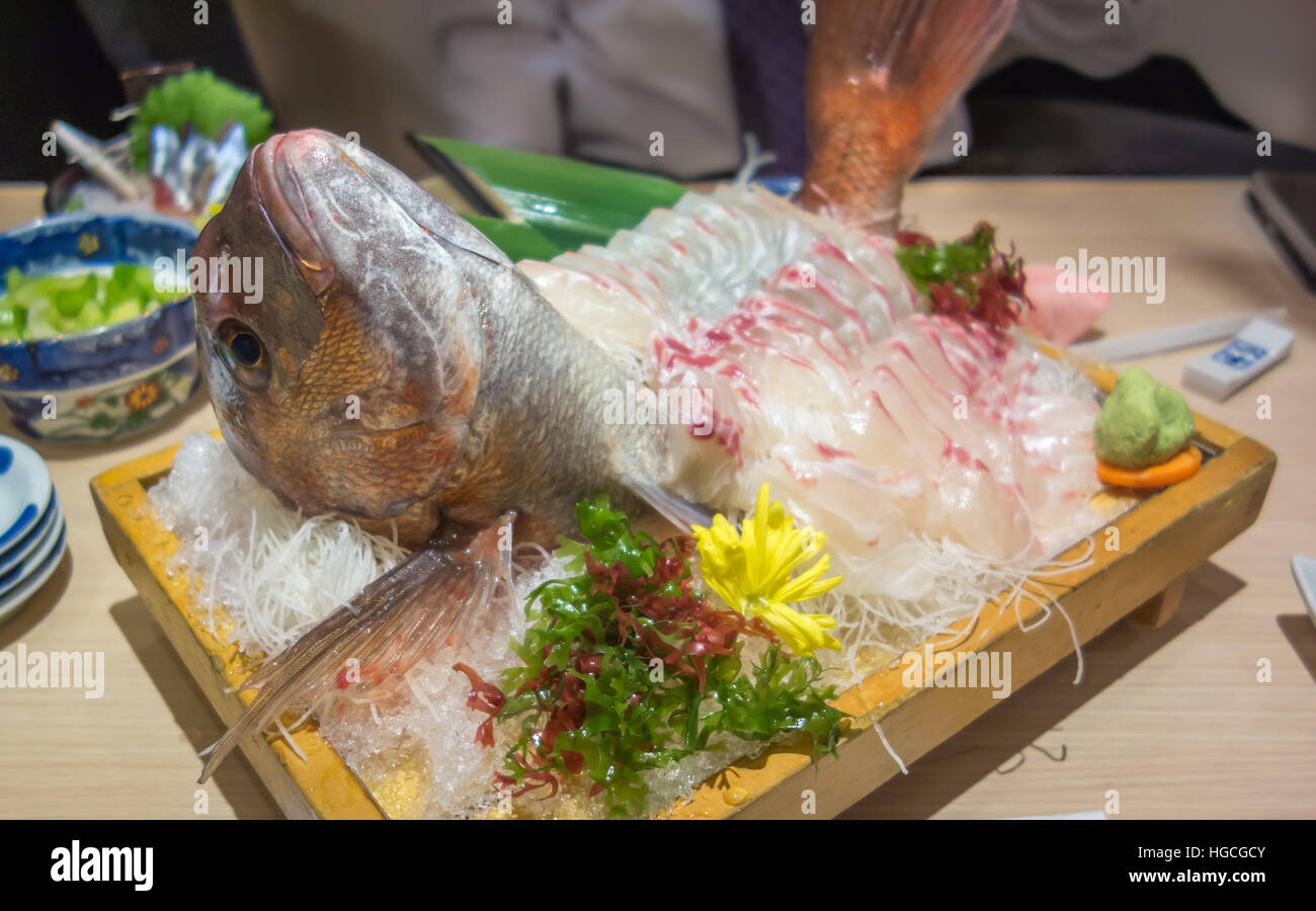 A decorated plate of red snapper freshly prepared as Japanese sashimi (raw fish) with a side of wasabi and seaweed. Stock Photo