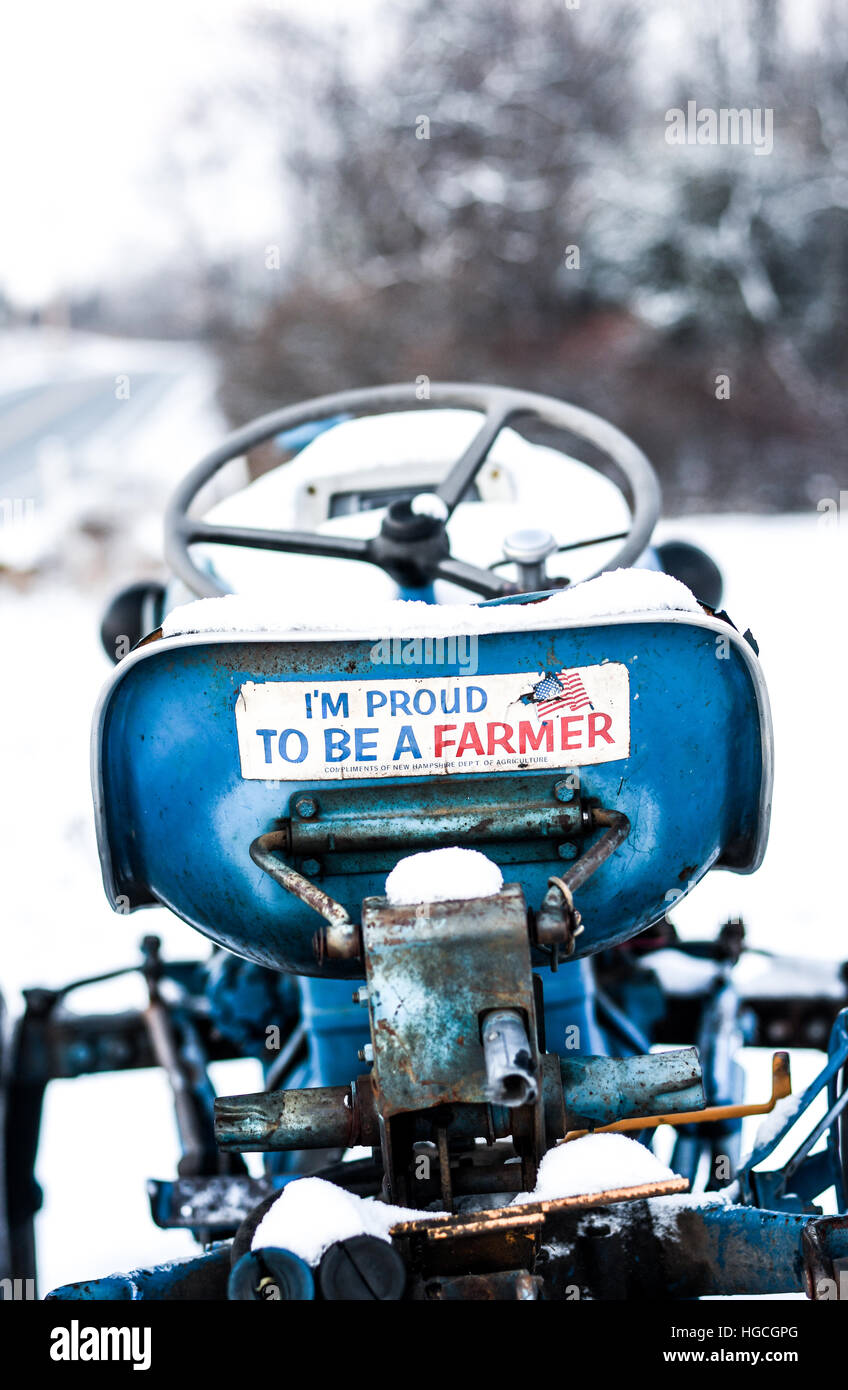 A farmer pride bumper sticker on a vintage blue Ford tractor in the snow Stock Photo