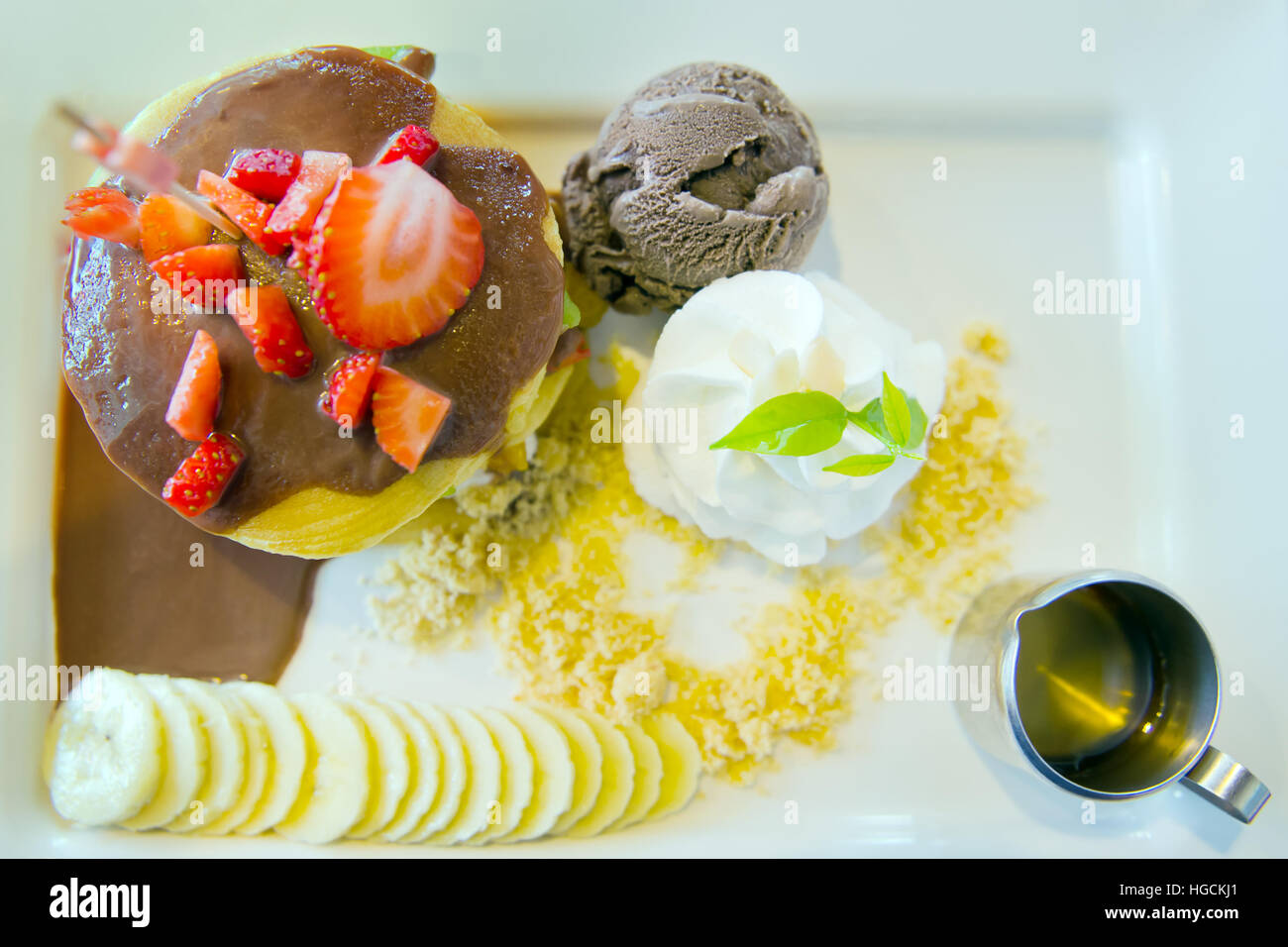 Low fat homemade chocolate ice-cream with strawberry, whip cream served with sliced banana, chocolate filled crepe and natural honey, a perfect sweet Stock Photo