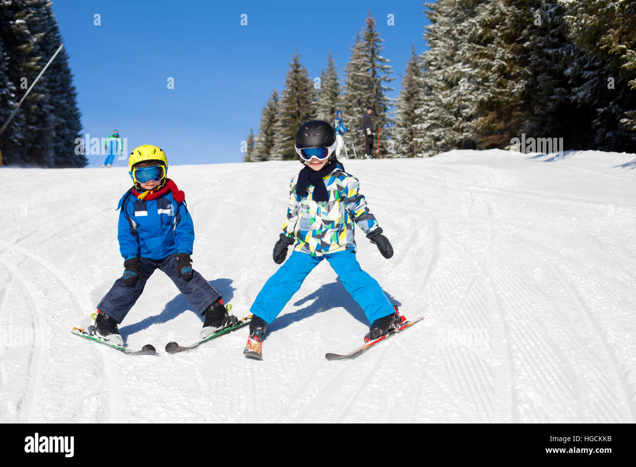 Two young children, siblings brothers, skiing in Austrian mountains on a sunny day, wintertime, enjoying sports Stock Photo