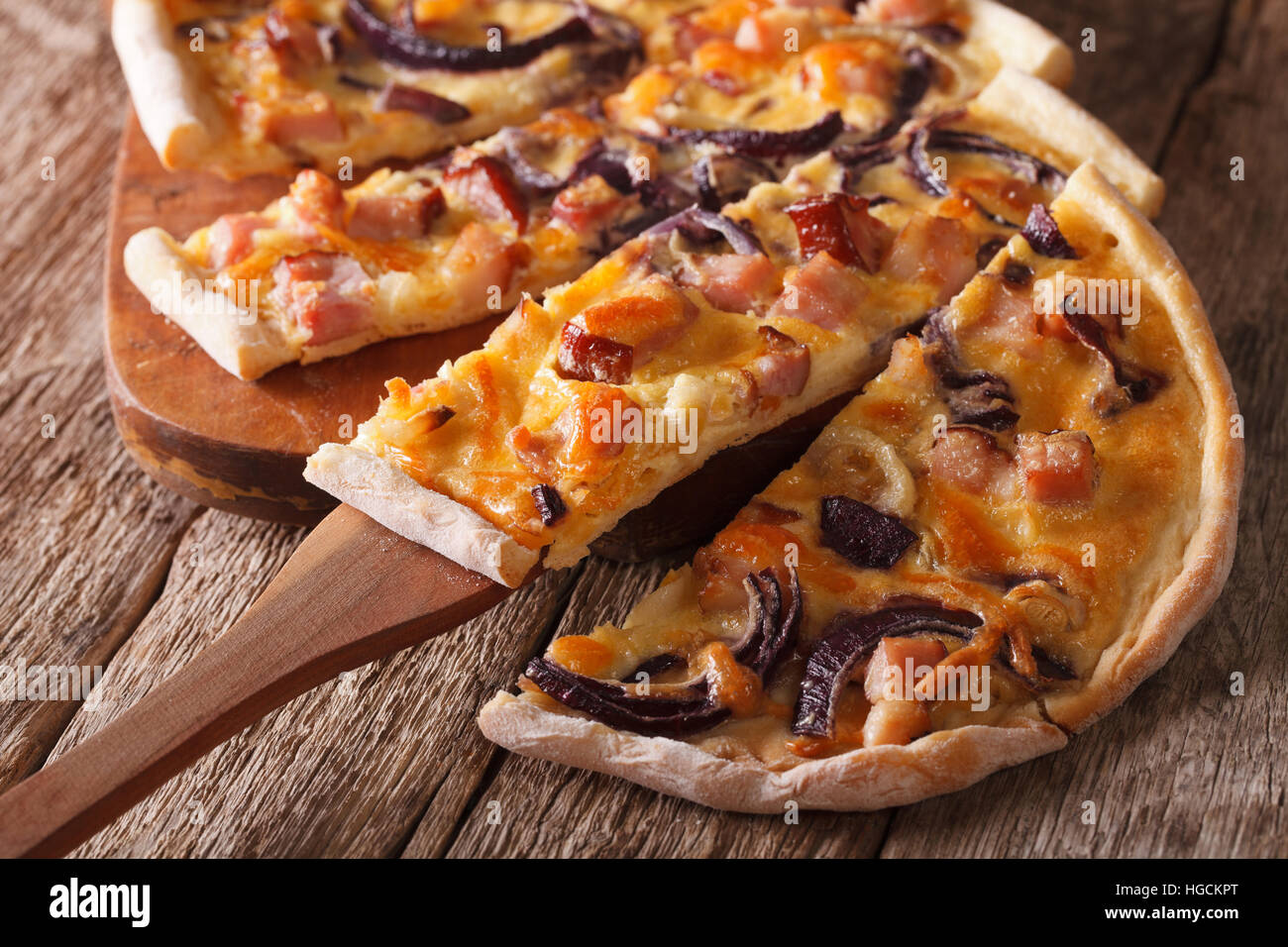 Alsatian pie flammkuchen chopped close-up on the table. Horizontal Stock Photo